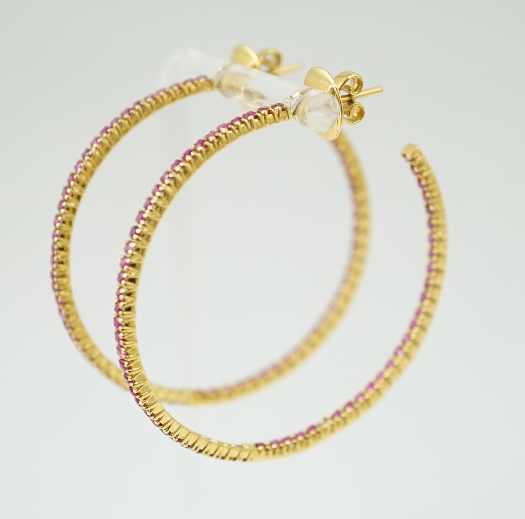 A large pair of gold and ruby chip set hoop earrings